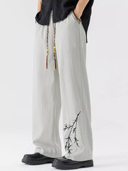 Light gray wide-leg sweatpants with black branch embroidery and braided drawstring.
