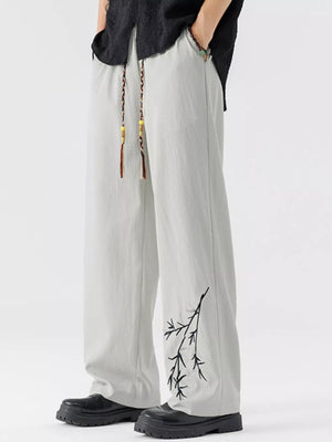 Light gray wide-leg sweatpants with black branch embroidery and braided drawstring.