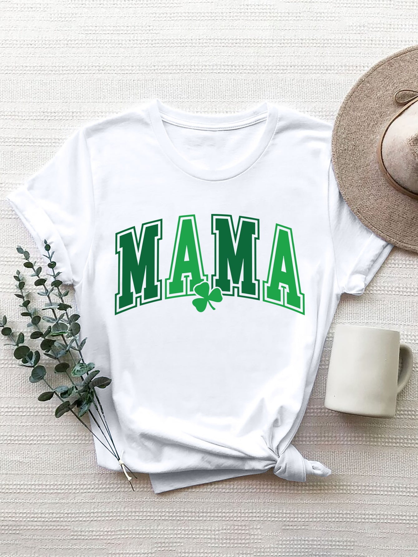 White graphic t-shirt with green "MAMA" text and shamrock detail