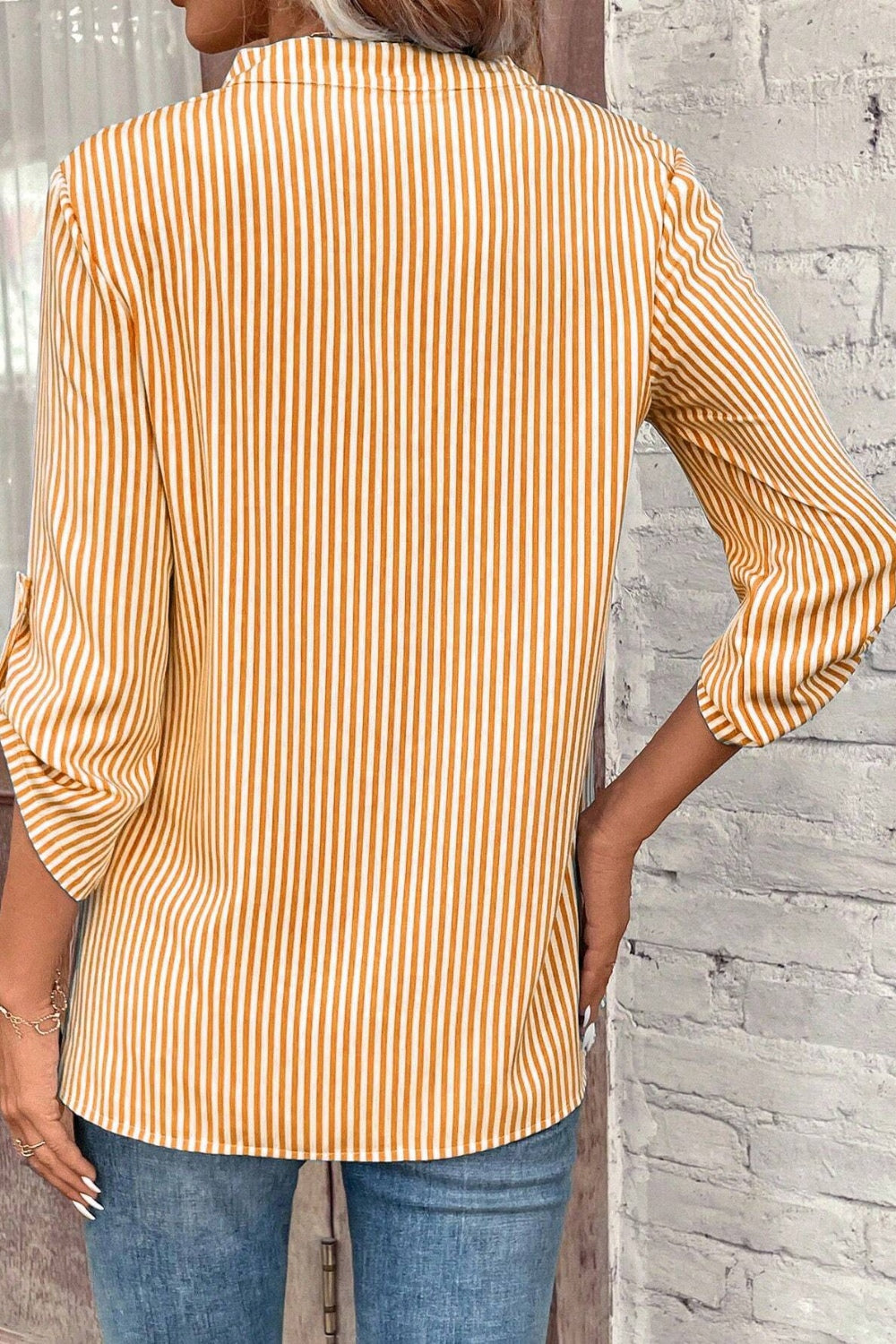 Gold and white vertical stripe blouse with rolled sleeves.