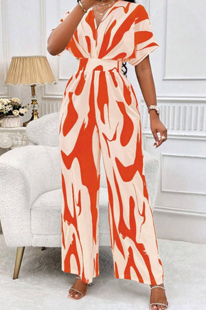 Orange and cream abstract brushstroke wide-leg jumpsuit with V-neck and short sleeves.