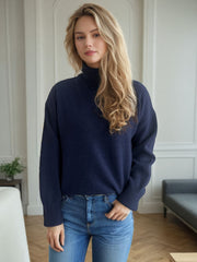 Dark blue relaxed fit turtleneck sweater with ribbed cuffs and hem, styled with jeans.
