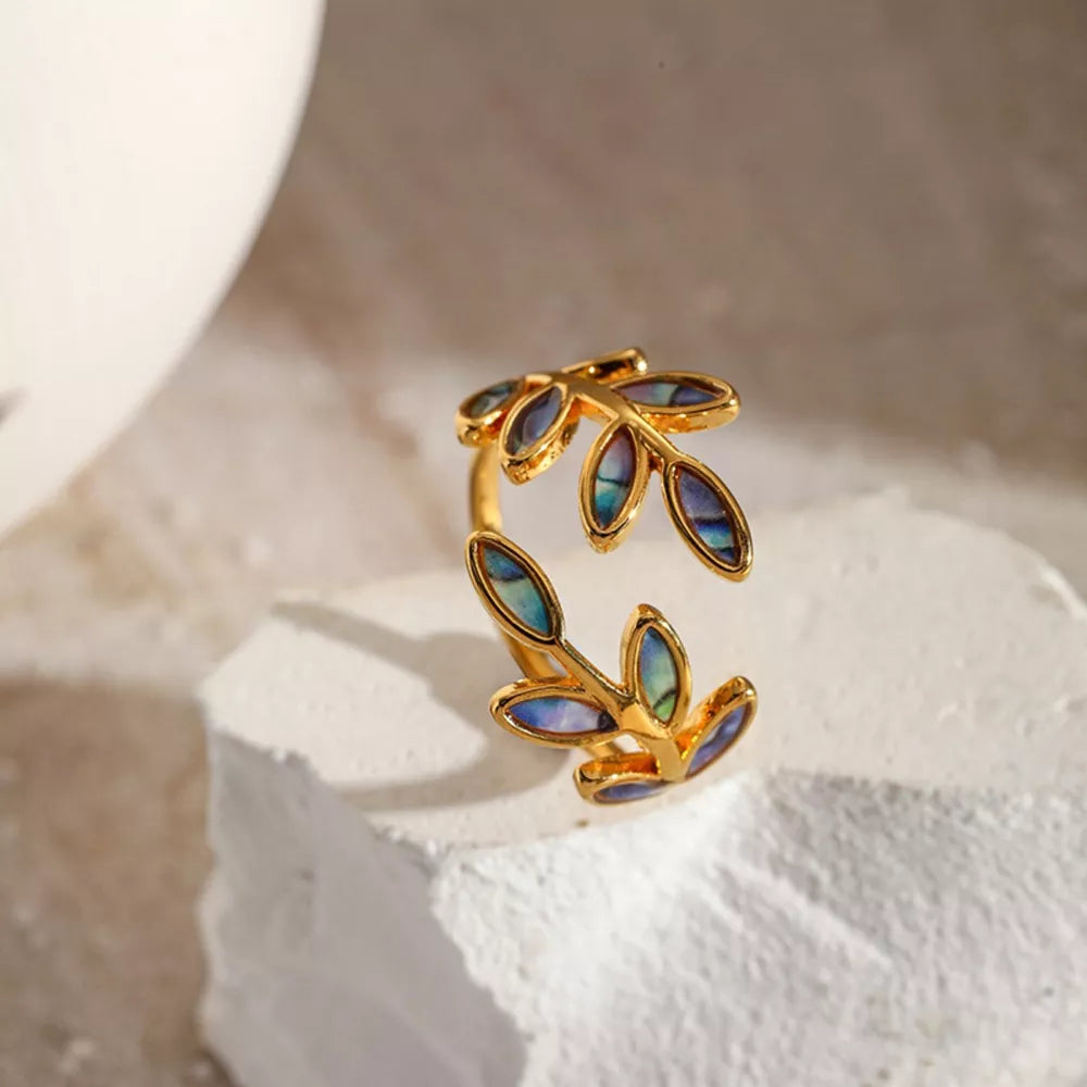 Gold bypass ring with leaf design and iridescent blue-green accents
