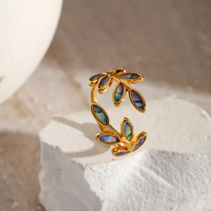 Gold bypass ring with leaf design and iridescent blue-green accents