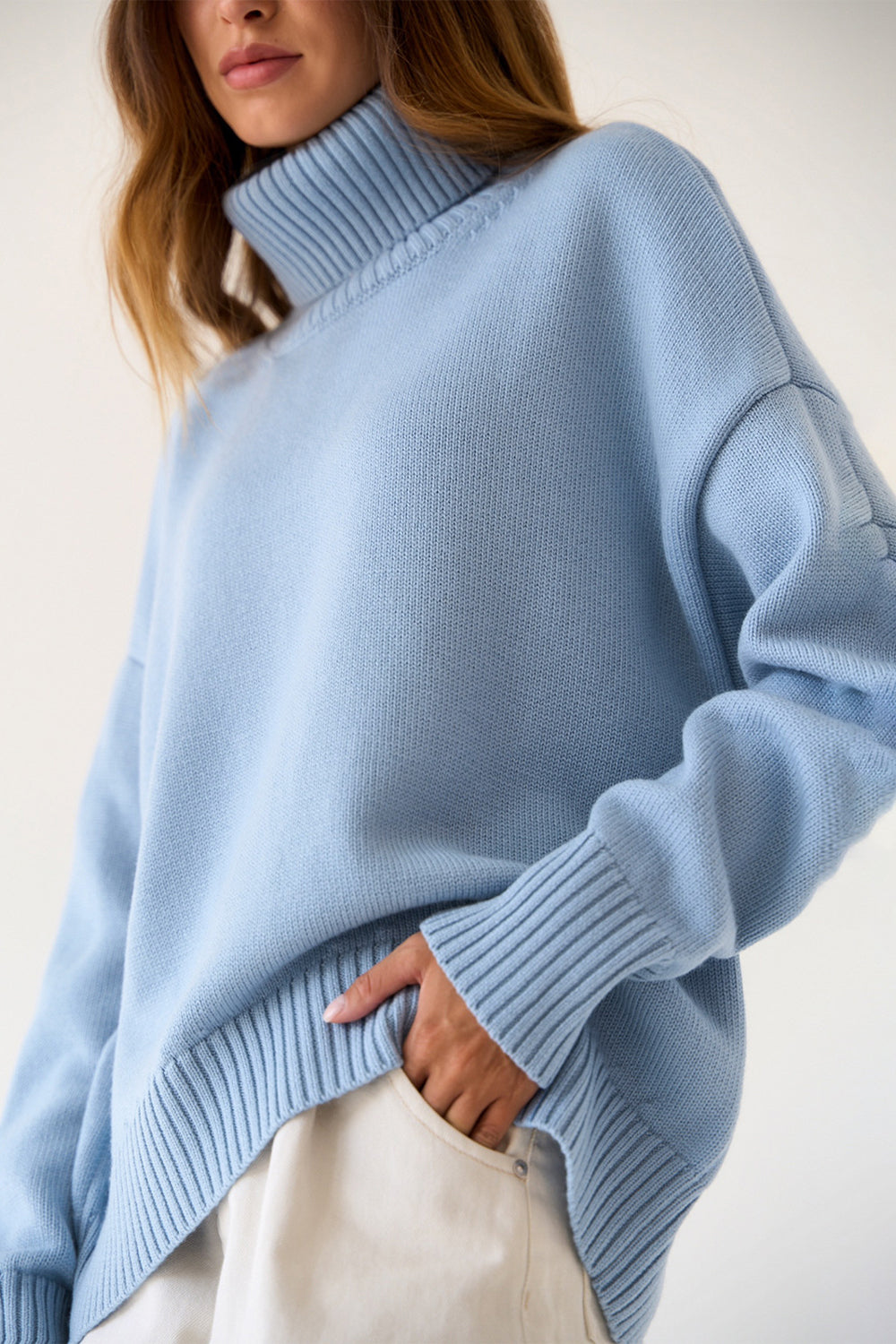Relaxed Misty Blue knit sweater with a boxy cut and roll-neck collar.