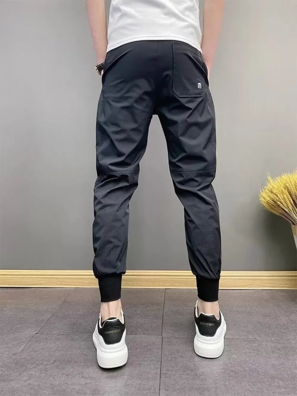 Black men's sweatpants with ankle cuffs and perforated detail.