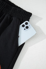 Black cotton sweatpants with elastic waist and phone pocket detail.