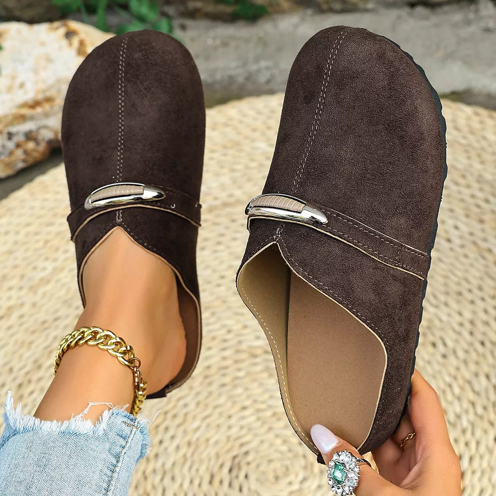 Brown slip-on flats with round toe and decorative buckle detail.