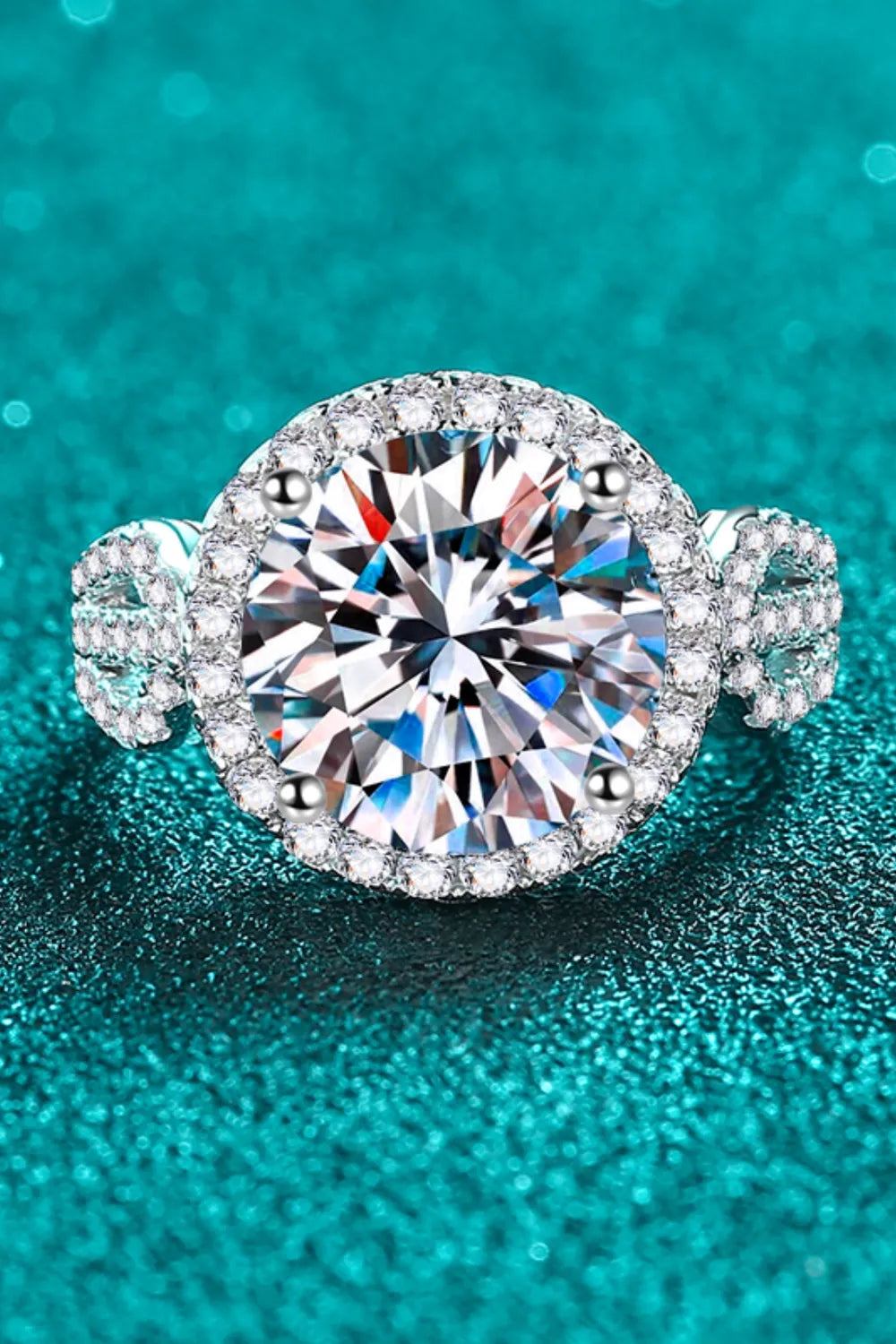 Silver halo moissanite ring with sculpted band and pavé accents.