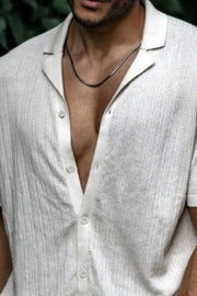 Textured ivory knit resort collar shirt with buttoned placket and short sleeves.