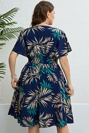 Dark navy midi dress with empire waist, flutter sleeves, and a tropical palm print.