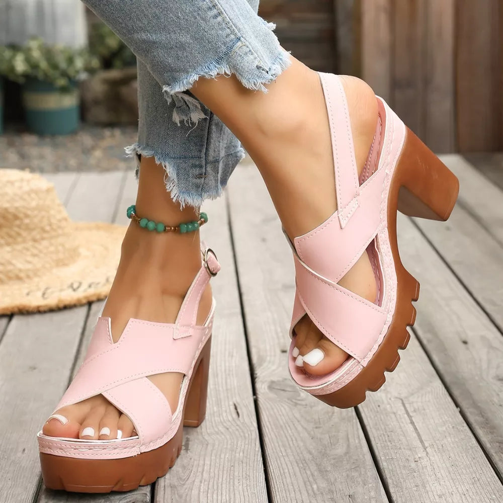 Pink open toe block heel sandals with cross straps and chunky sole.