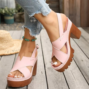 Pink open toe block heel sandals with cross straps and chunky sole.