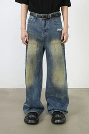 Faded patchwork denim palazzo trousers in medium wash with distressed details and wide legs.