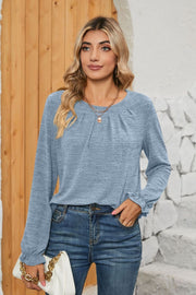 Light blue knit top with ruffled cuffs and pleated yoke detail.