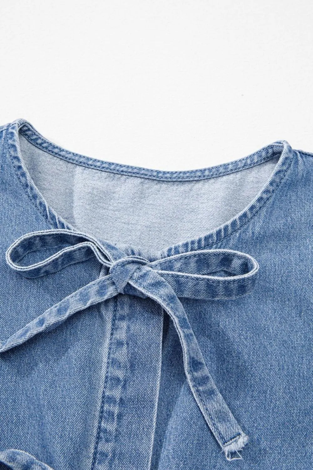 Denim peplum blouse in medium wash with a tie-neck detail