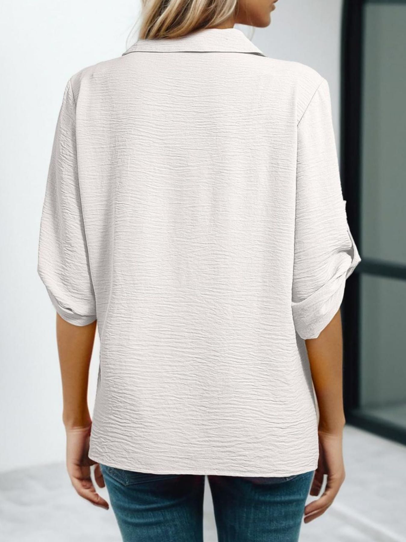 White textured V-neck blouse with roll-up sleeves and a button-down front.