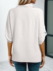 White textured V-neck blouse with roll-up sleeves and a button-down front.