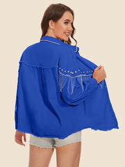 Royal blue trucker jacket with fringe and pearl embellishments on shoulders and frayed hem.
