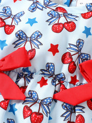 Baby one-piece with cherry, bow, and star print in light blue cotton, featuring red ruffle trim.