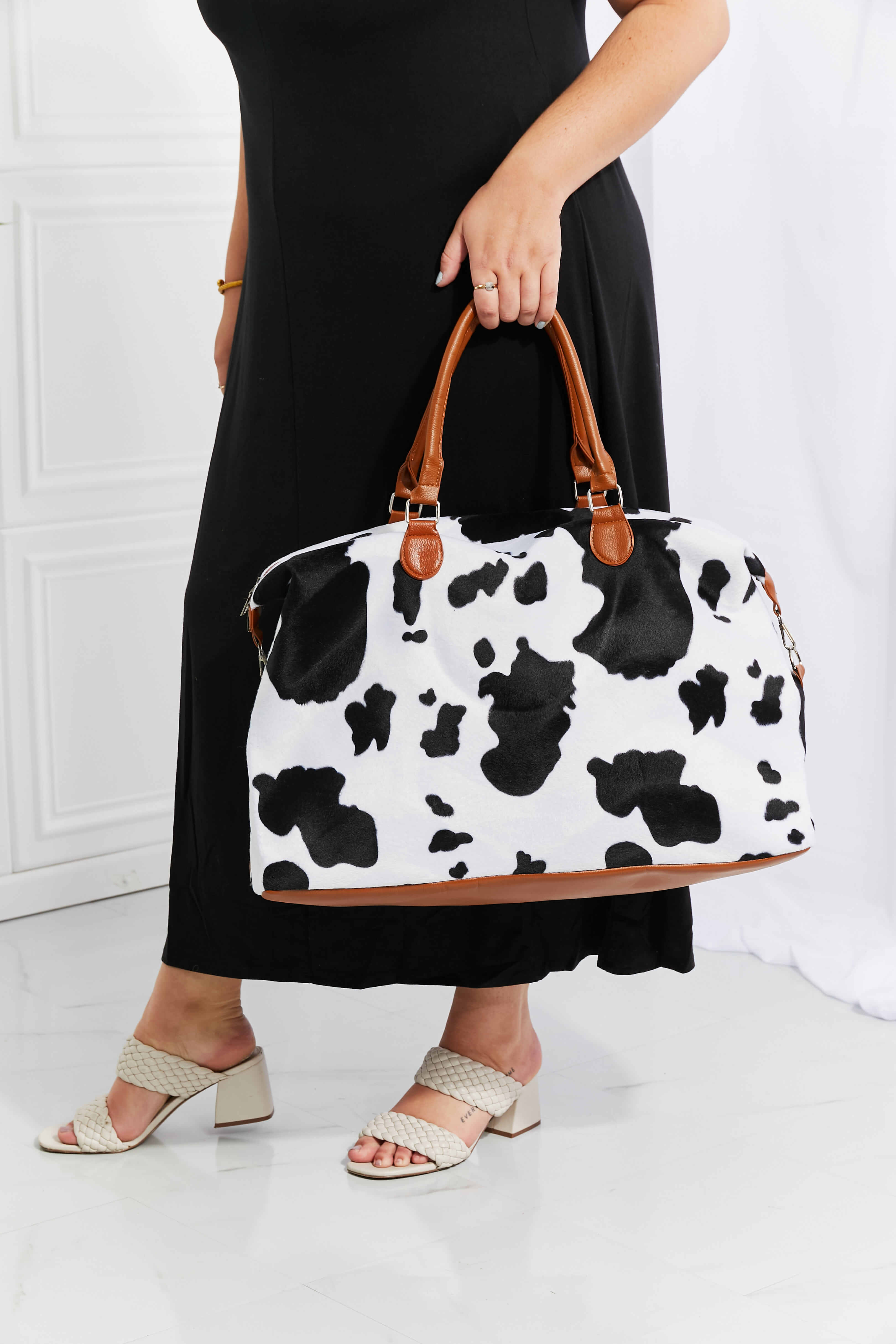 Cowhide print duffel bag with brown leather trim and handles