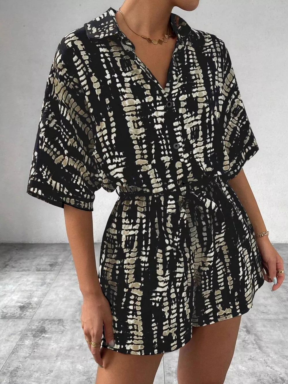 Black and cream tie-dye belted romper with collared neckline and button front.