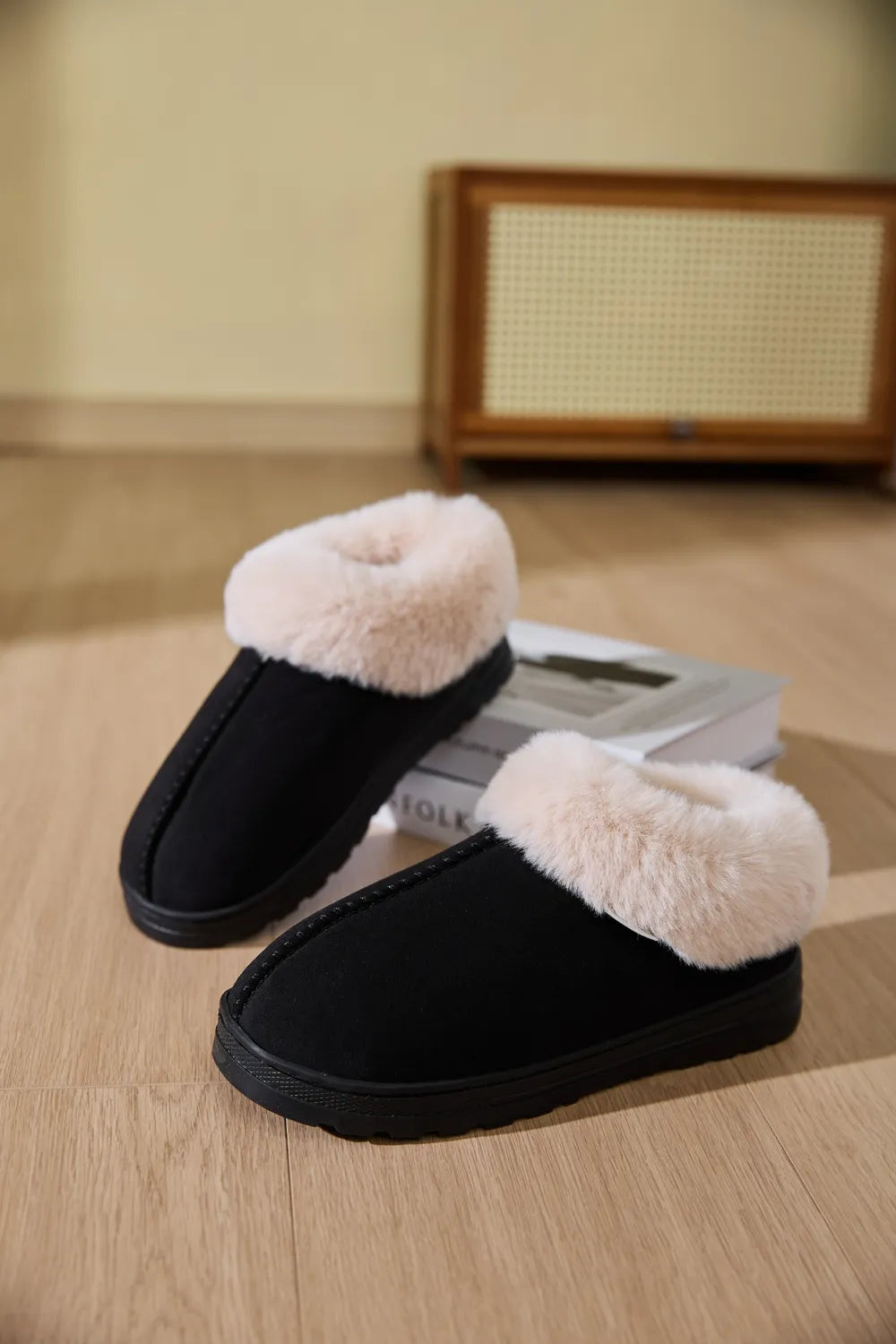 Black suede slippers with plush shearling trim, perfect for cozy loungewear.