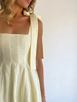 Yellow bow-tie shoulder maxi dress with square neckline and pleated skirt detail.
