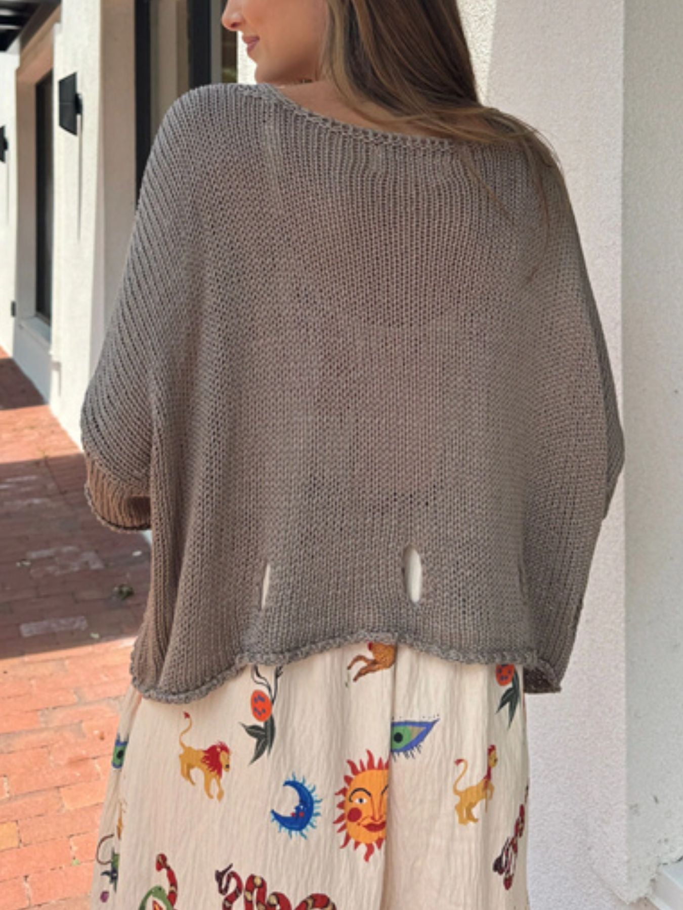 Distressed knit pullover sweater with cutout details and asymmetrical hem.