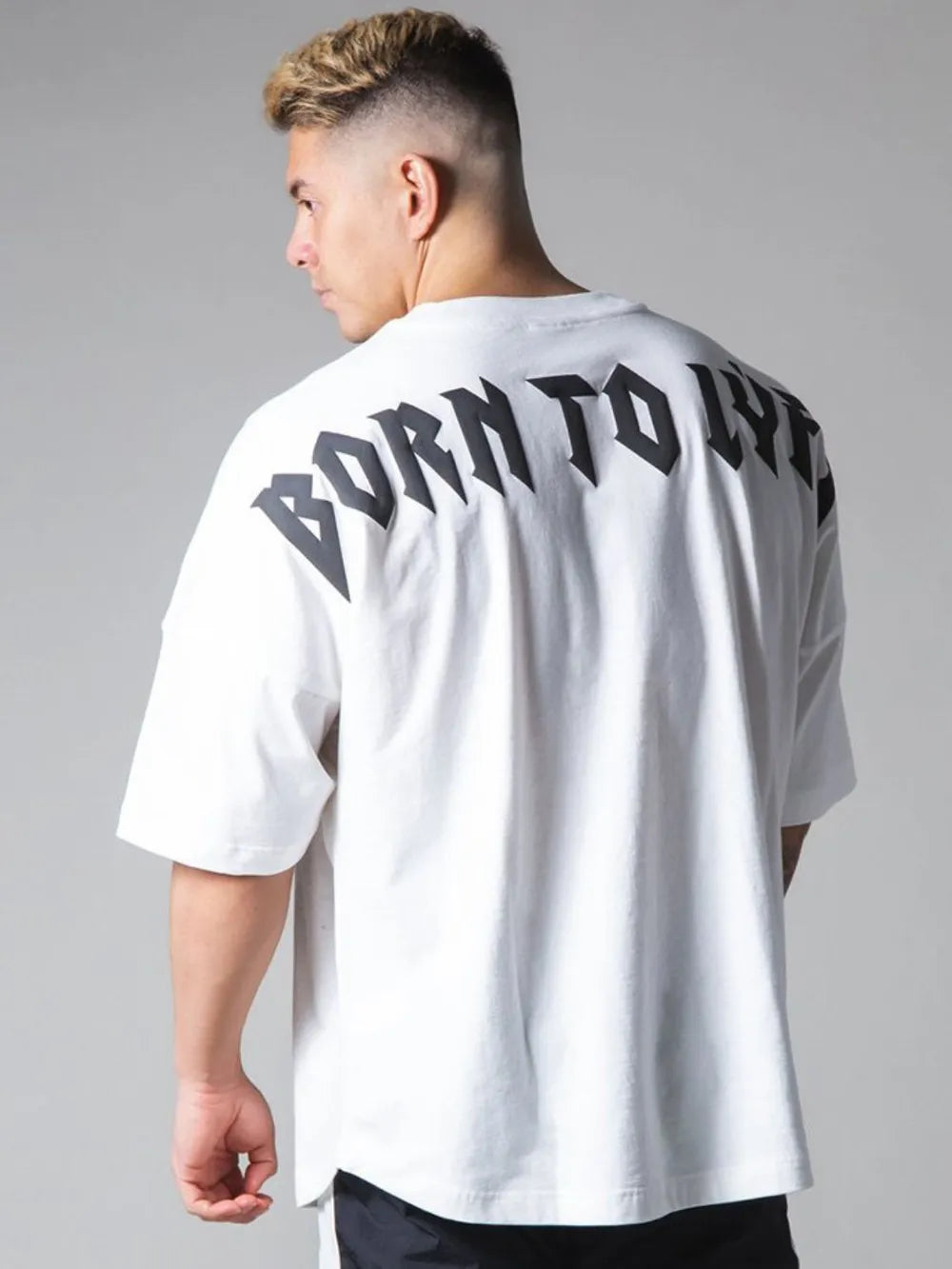 Oversized white graphic tee with black "BORN TO LIVE" text on back.