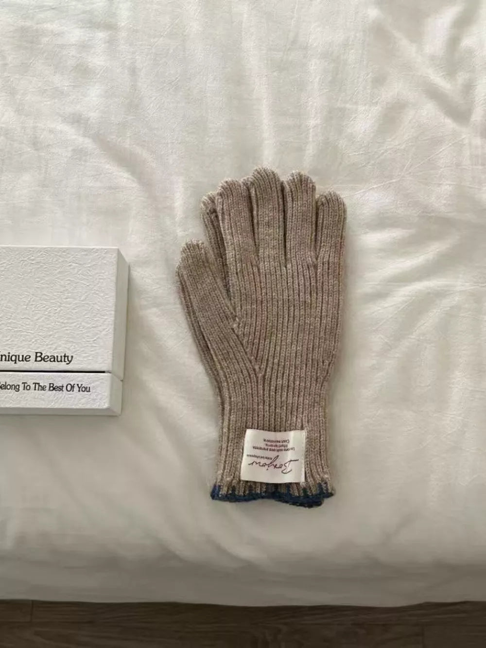 Brown ribbed knit gloves with blue trim and a scalloped cuff detail.