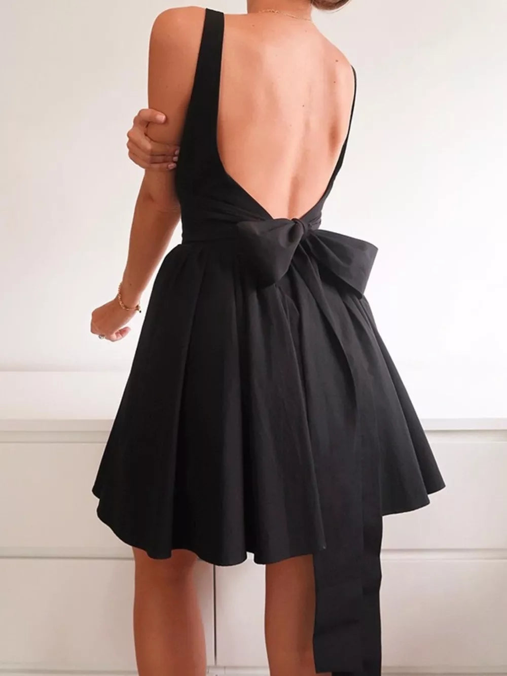 Black backless mini dress with square neck and large bow detail on back