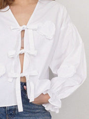 White blouse with heart appliqué and tie front, ruffled cuffs.