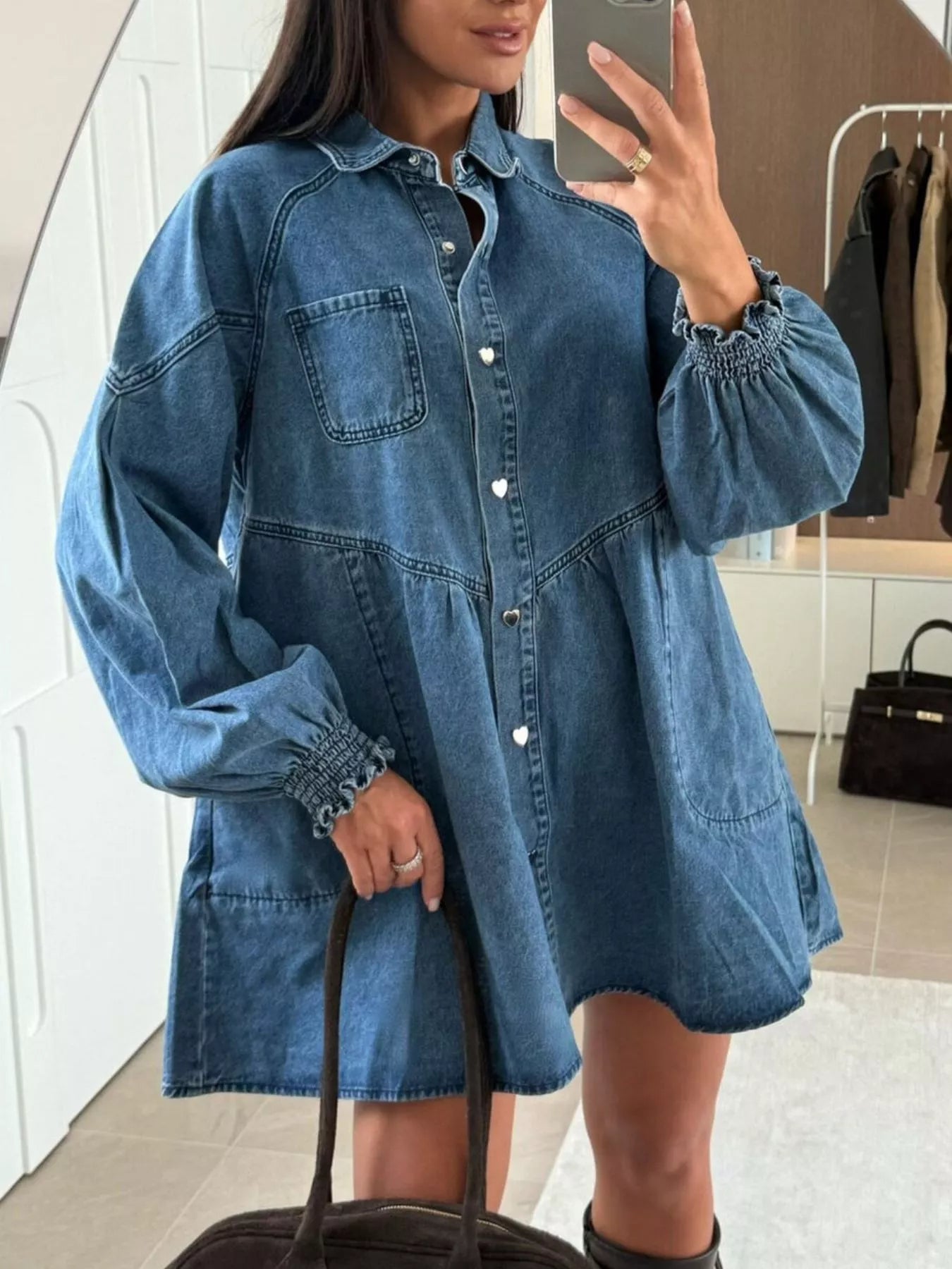 Blue denim mini dress with pockets, button-down front, and smocked cuffs.