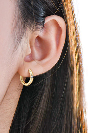 Gold pavé point huggie hoop earring with a single clear stone detail.
