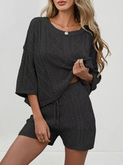 Black cable-knit two-piece sweater set with drawstring shorts and a relaxed-fit top.