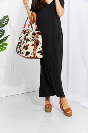 Cowhide print duffel bag with brown leather trim and straps
