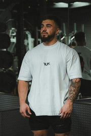 Oversized white graphic tee with black statement logo and short sleeves.