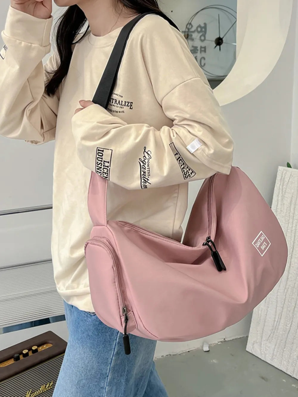 Slouchy crescent crossbody bag in Dusty Pink with adjustable strap and multiple zippered pockets.
