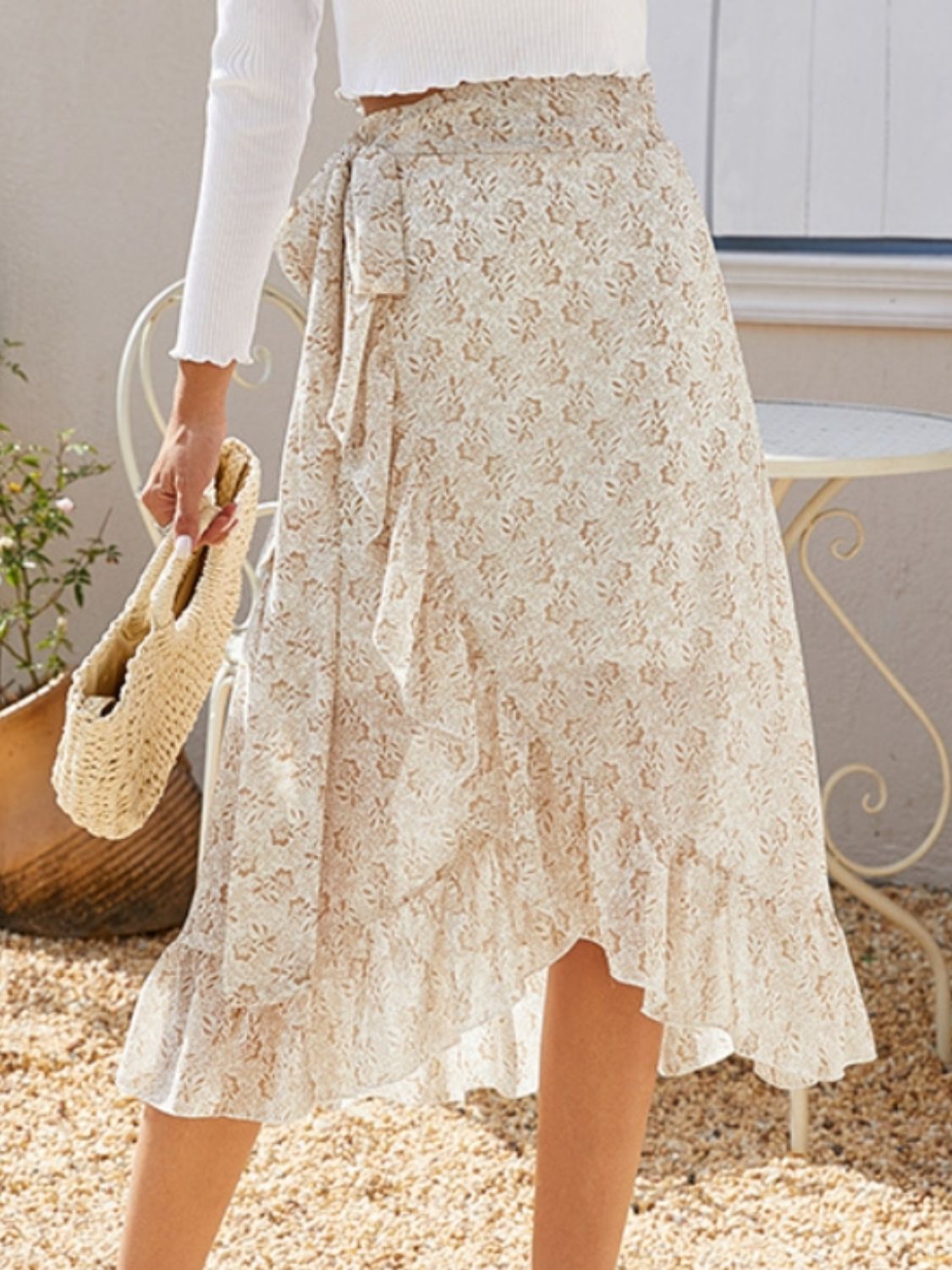 Asymmetric wrap skirt in cream with a subtle leaf print and ruffled hem.