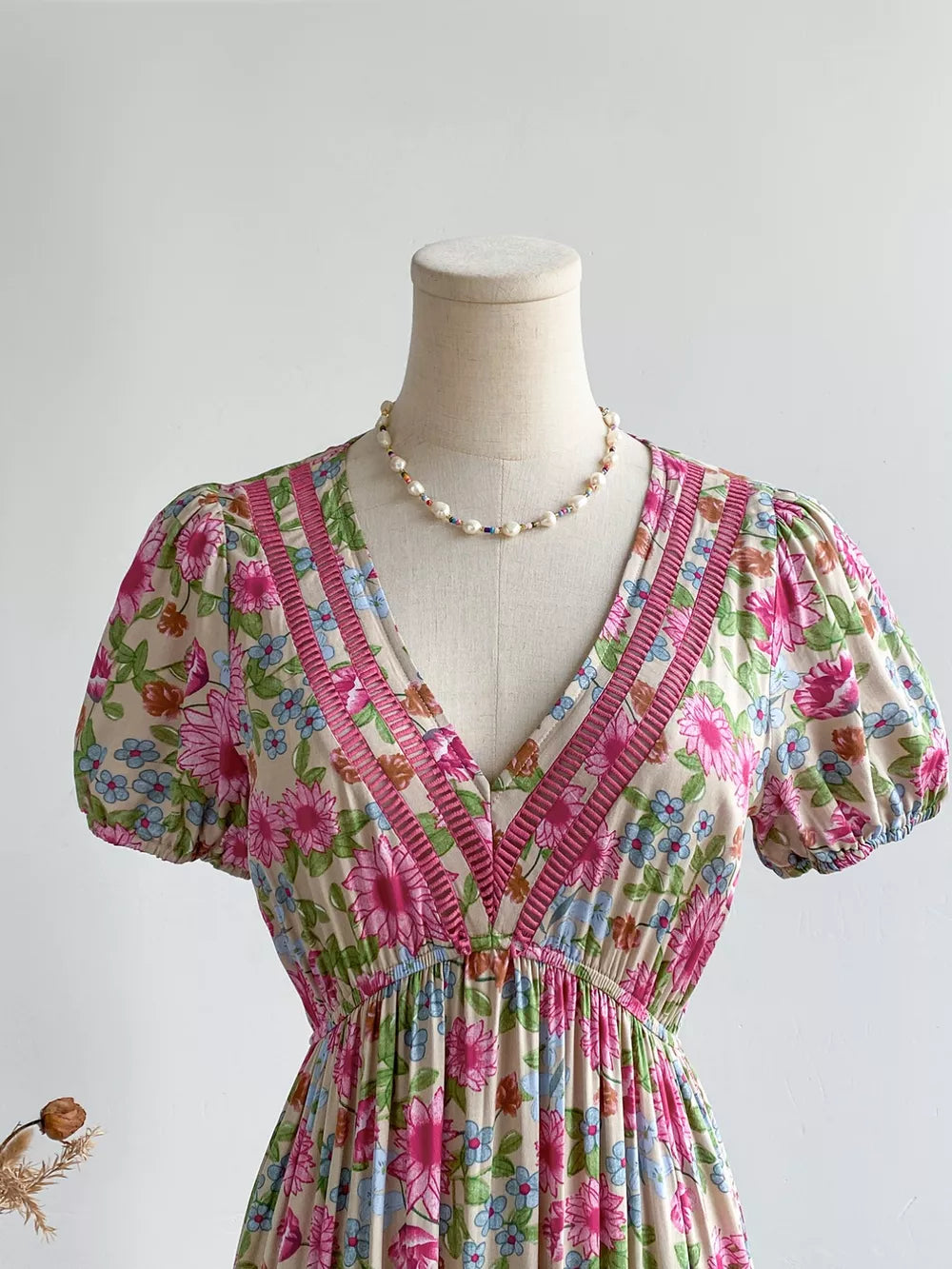 Maxi dress with V-neck, short puff sleeves, and a floral print with decorative trim.