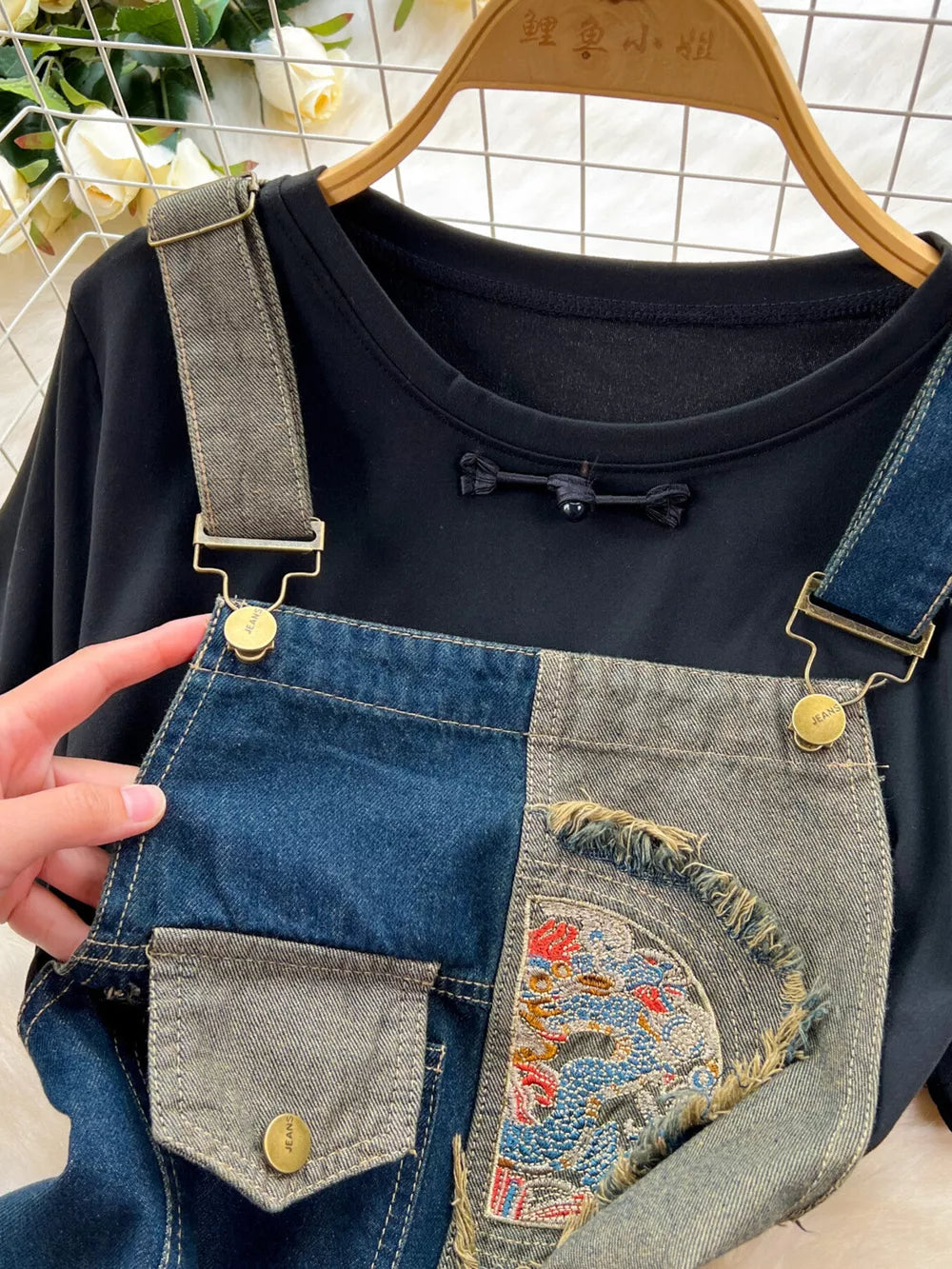 Black knotted tee with distressed patchwork denim overalls featuring dragon embroidery.