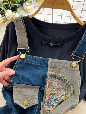Black knotted tee with distressed patchwork denim overalls featuring dragon embroidery.