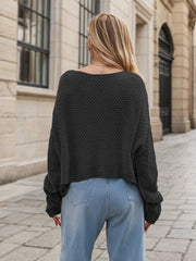 Black acrylic cable knit cocoon sweater with a wide neckline and relaxed fit.