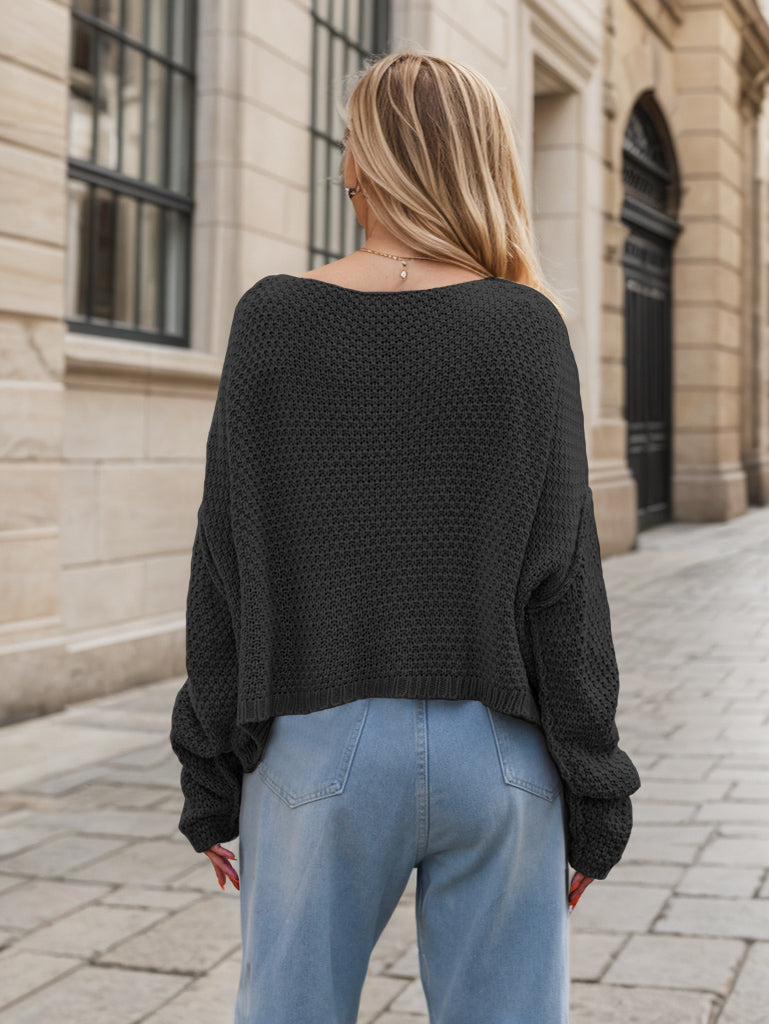 Black acrylic cable knit cocoon sweater with a wide neckline and relaxed fit.