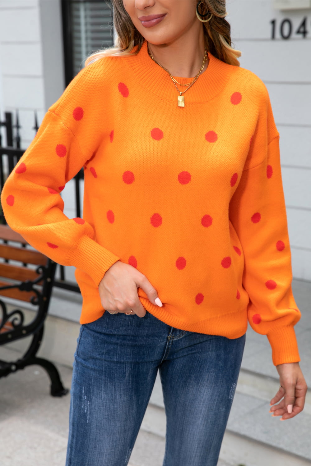 Orange polka dot knit sweater with balloon sleeves and mock neck.