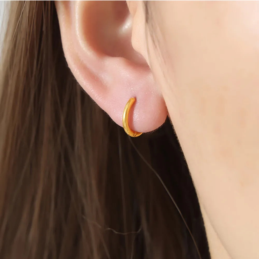 Gold vermeil huggie earrings, small hoop style, worn on earlobe.