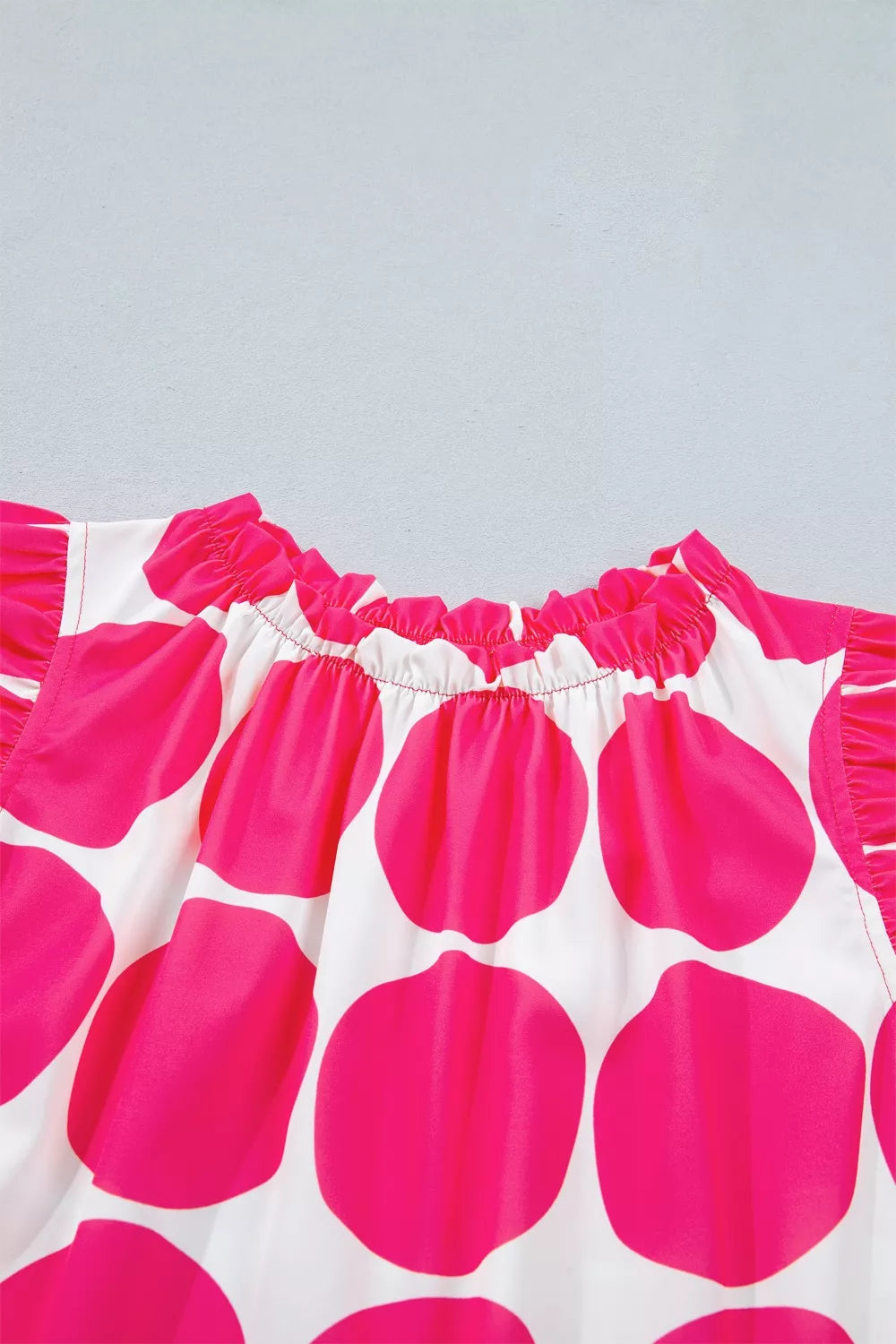 White and pink polka dot tank top with frill neckline and sleeves.