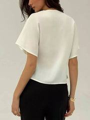 White asymmetrical V-neck short sleeve buttoned shirt with a relaxed fit.