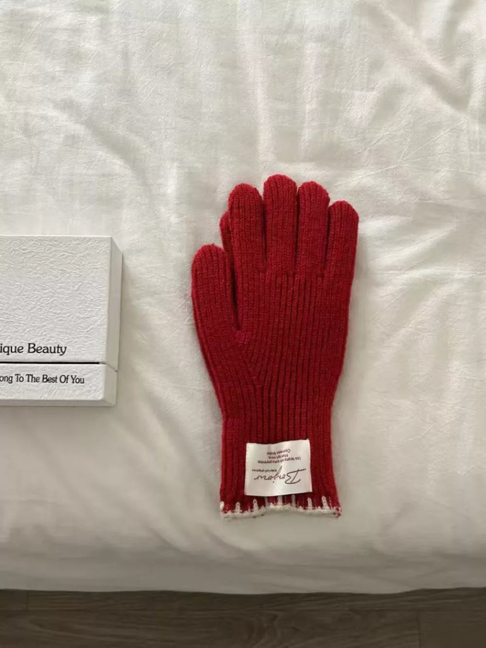 Red ribbed knit gloves with white scalloped cuff detail and label.